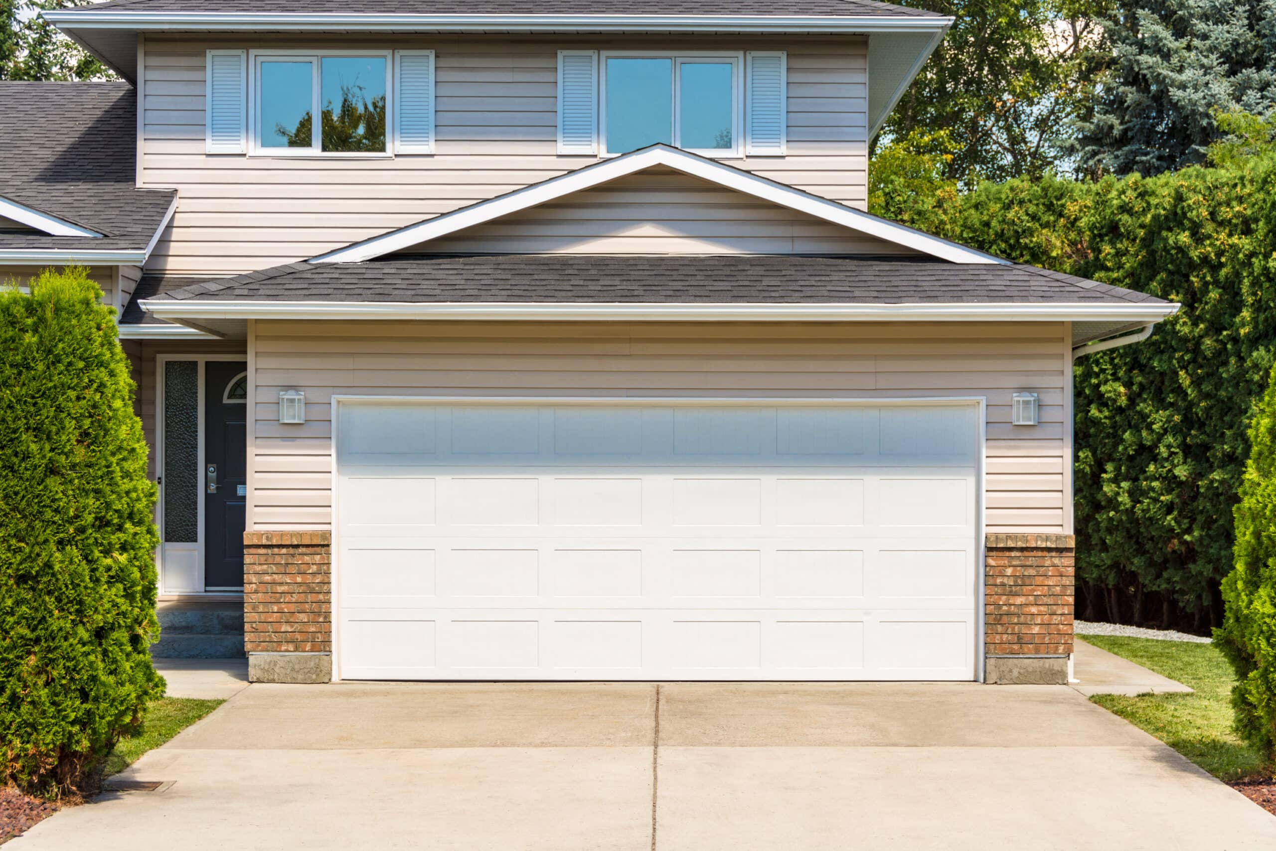 White wide garage door of residential house with concrete drivew